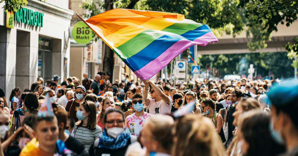 person waving rainbow flag in the middle of crowd