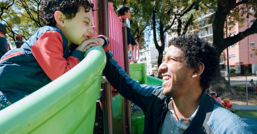 latino father playing with son at park