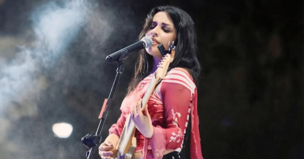 woman singing on stage with guitar