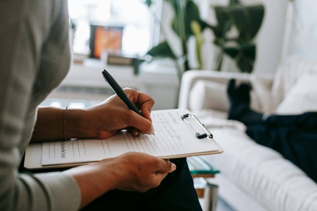 woman taking notes in therapy session