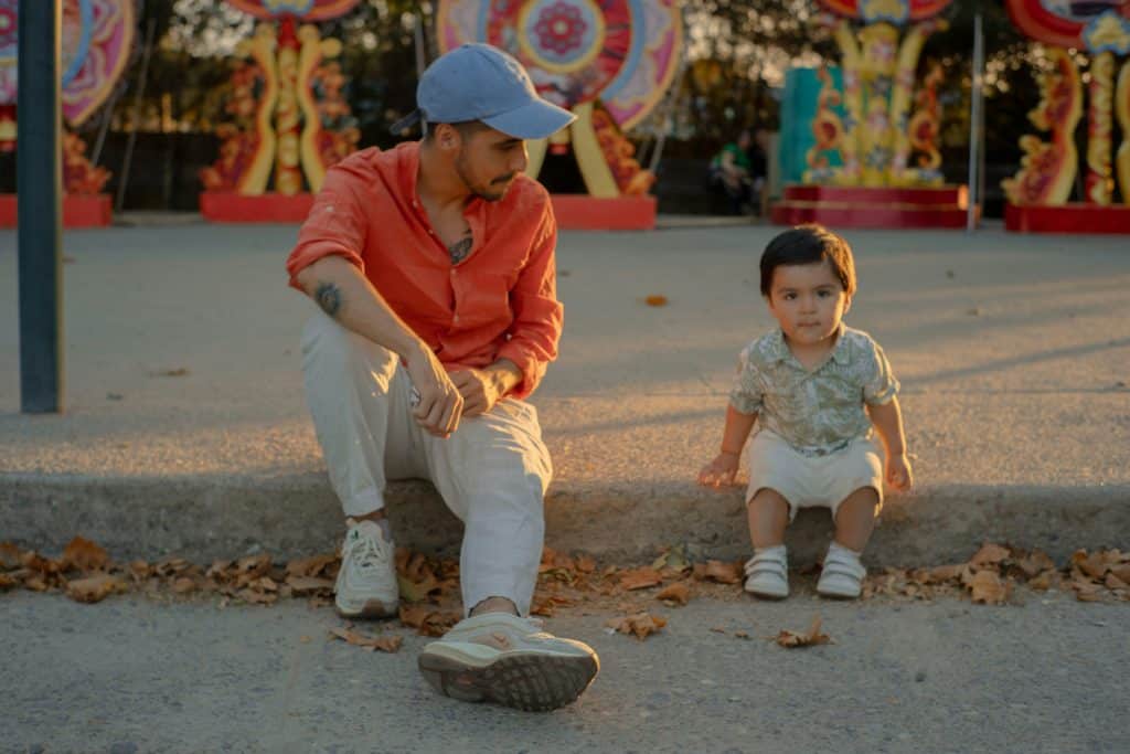 father and son sitting down on a curb
