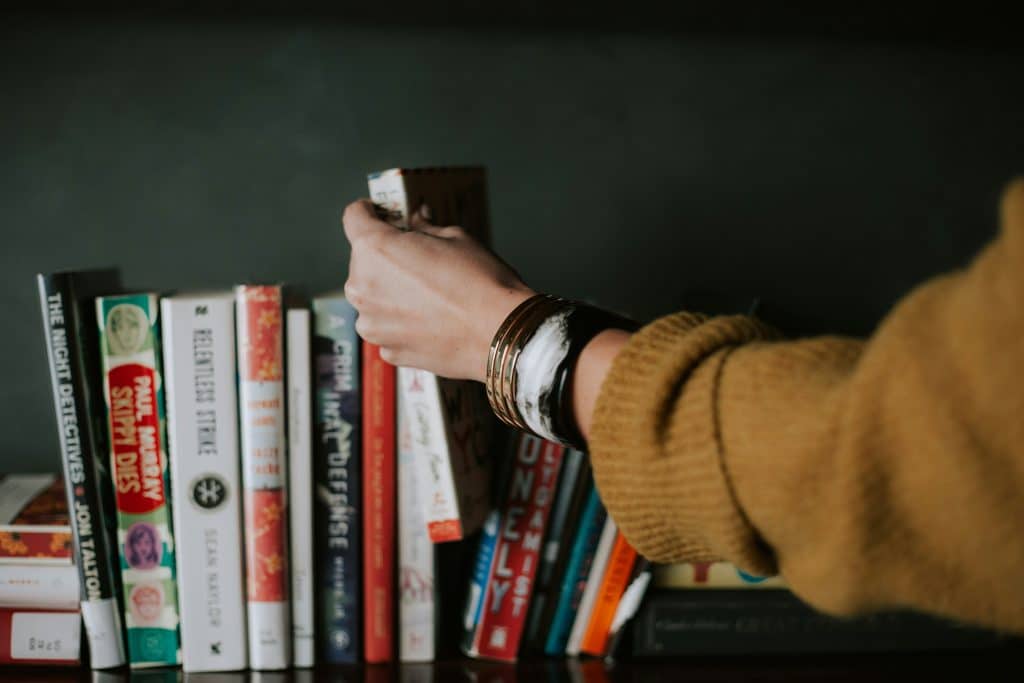 hand grabbing a book from the shelf
