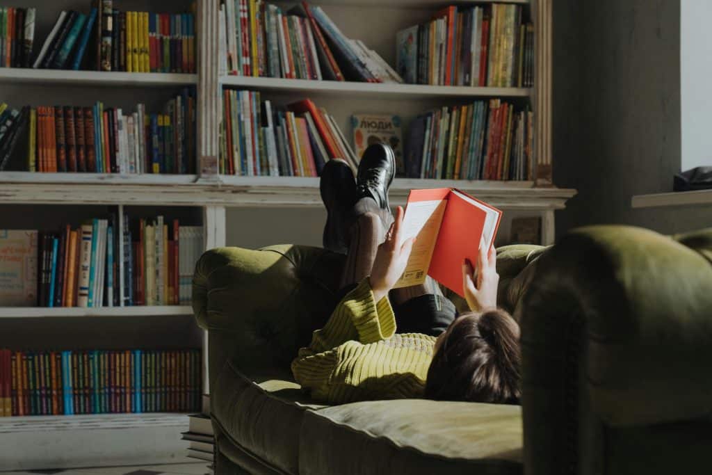 woman reaching book in couch