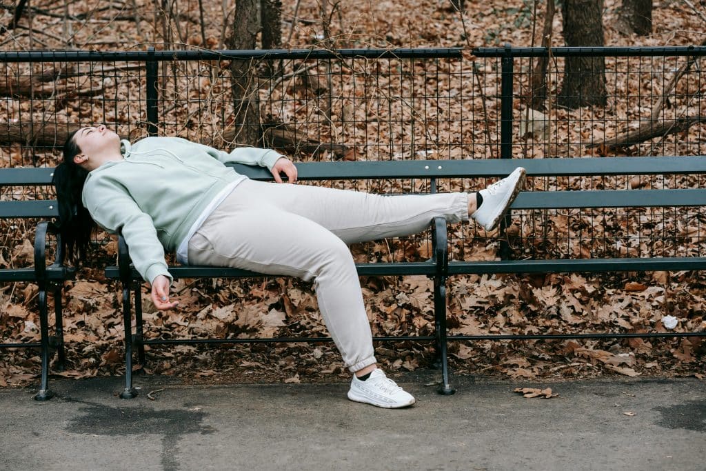 woman laying on a public bench