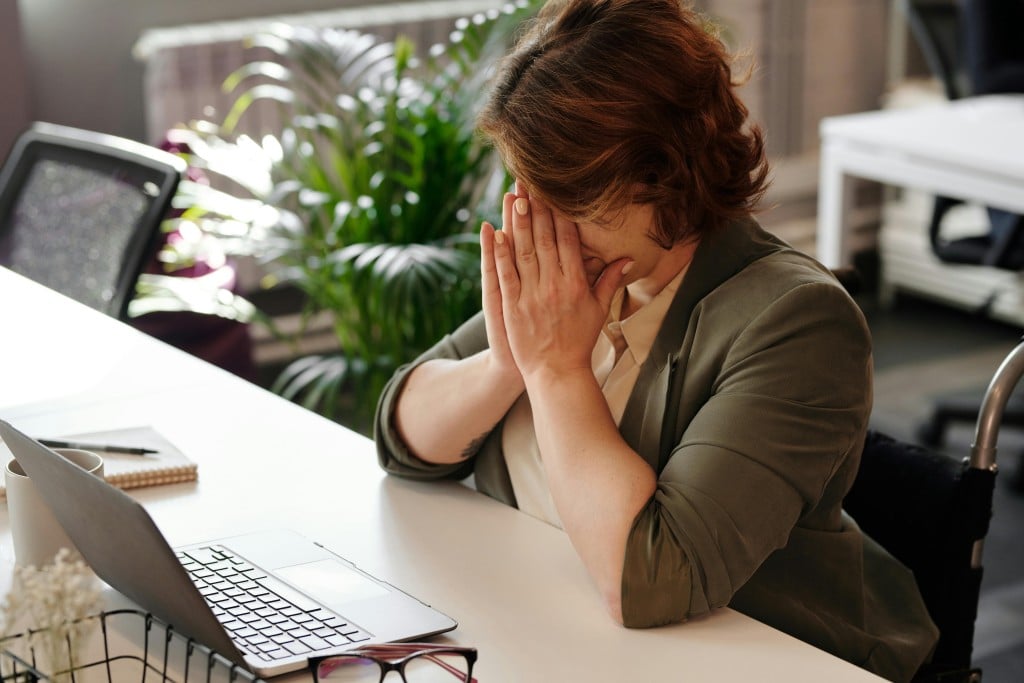woman sitting at desk covering her face