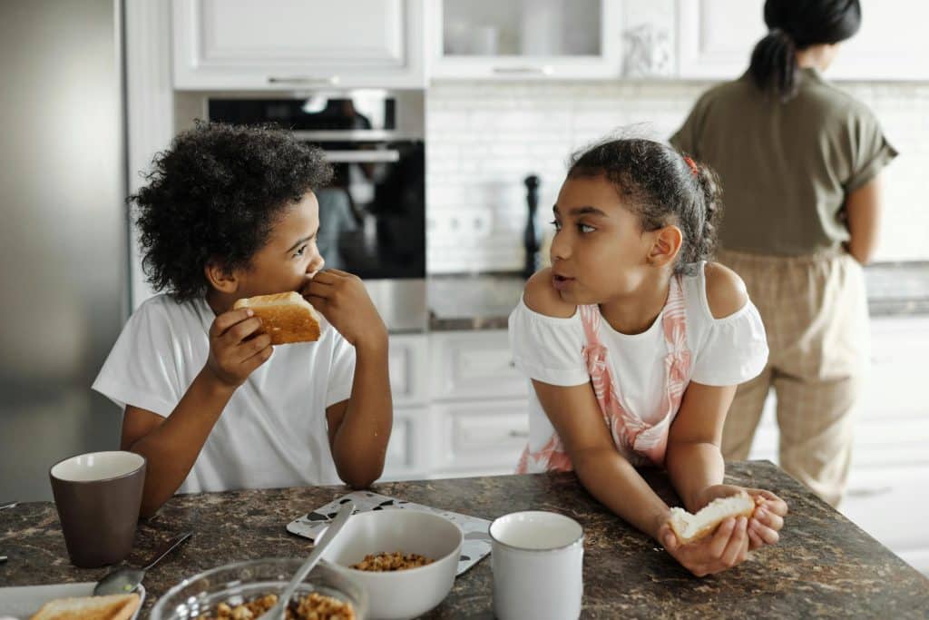two girls eating toast in the kitchen