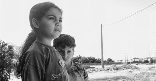 two children looking uncertainly towards the horizon