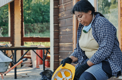 woman sitting and holding a construction work hat