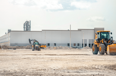 A large construction site featuring heavy machinery and industrial building in progress.