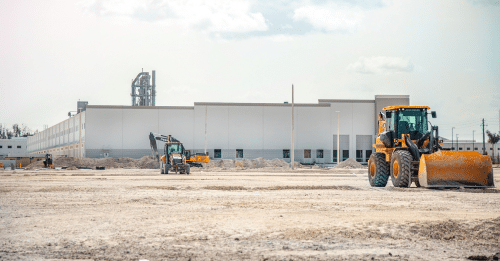 A large construction site featuring heavy machinery and industrial building in progress.