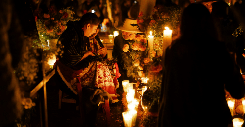 people gathered around a day of the dead altar