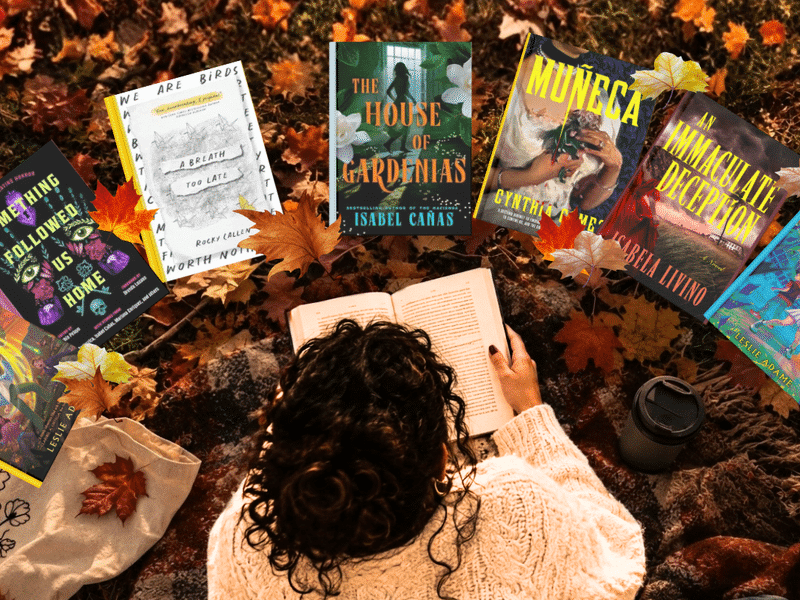 woman laying over fall leaves reading a book